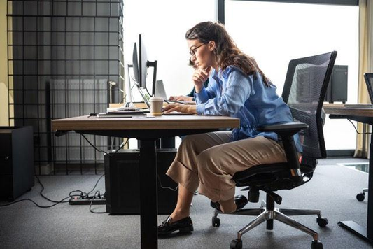 Woman sitting at office desk with forward head posture while working on computer